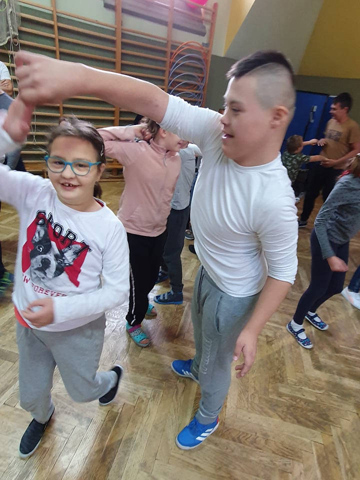 Dwoje uczniów tańczy na sali gimnastycznej.